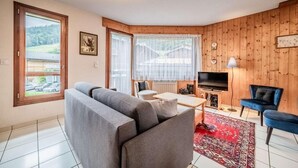 Un salon avec un canapé, un téléviseur et un mur en bois.