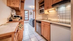 Une cuisine compacte dotée de meubles en bois, d’un four à micro-ondes et d’un lave-vaisselle.