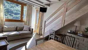Una sala de estar acogedora con un sofá, una mesa de comedor y una escalera que sube a un nivel superior.