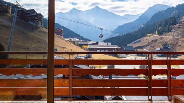 A mountain view from a wooden balcony with a cable car in the distance.