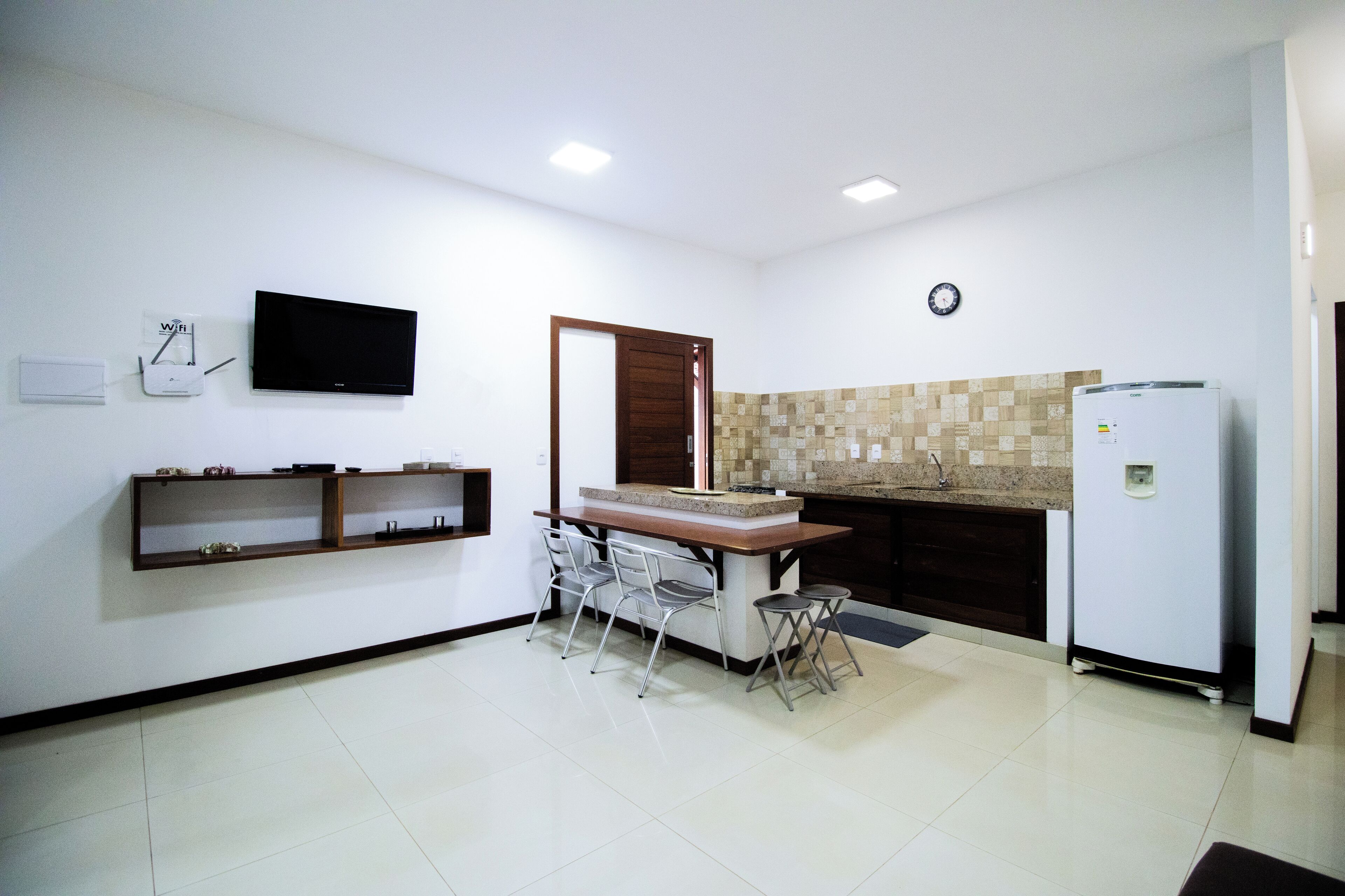 A compact kitchen with a built-in refrigerator, a microwave, and a sink. There is a small dining area with a table and chairs.