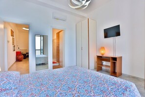 Une chambre à coucher avec un lit, une télévision, une armoire et un miroir.