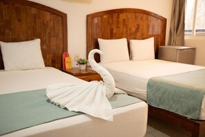 Two beds with wooden headboards, a towel shaped like a swan, and a small table with a plant and a bottle. - Casa Calendario Azteca (Playa del Carmen)