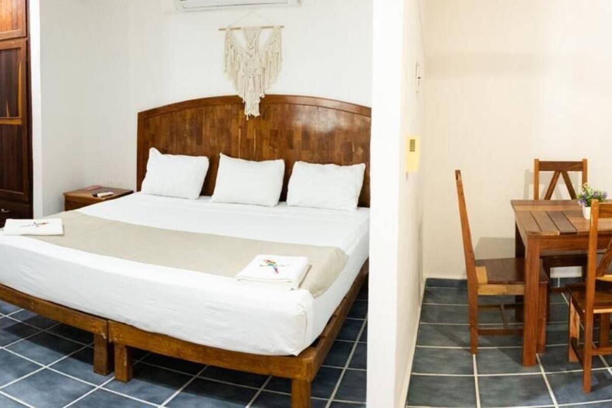 Une chambre à coucher avec un lit en bois, une table de chevet en bois, une chaise en bois et une petite table.