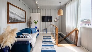 A modern living room with a sofa, a TV, and a staircase leading to an upper floor. - House Near the Beach and Beto Carrero Efp0356 (Penha)