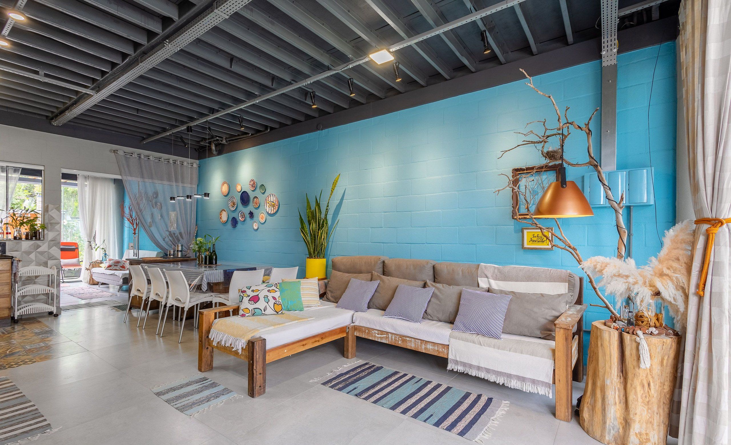 Ein modernes Wohnzimmer mit blauer Akzentwand, einer Couch, einem Couchtisch und einem Essbereich mit Stühlen und einem Tisch.