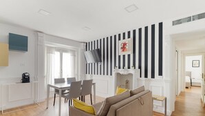 Un salon moderne comprenant un canapé, un téléviseur à écran plat, une cheminée et un coin repas avec des chaises et une table.