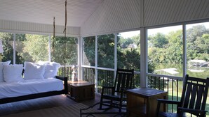 Une chambre avec une grande fenêtre donnant sur un lac, un lit, une table et une chaise.