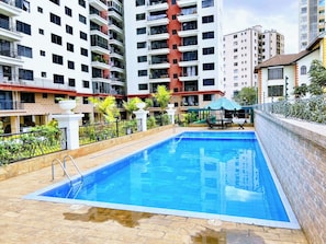 Ein rechteckiger Swimmingpool mit glasklarer blauer Wasseroberfläche, umgeben von einer gefliesten Liegefläche und einer niedrigen Mauer.
