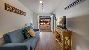 Una sala moderna con un sofá gris, un mueble de televisión de madera y un ventilador de techo.
