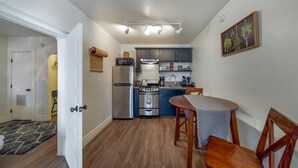 Una cocina compacta con electrodomésticos modernos, una zona de comedor con mesa y sillas, y un pasillo que conduce a otra habitación.