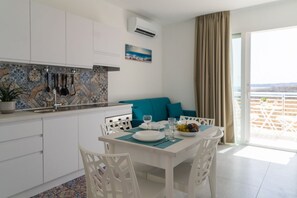Une cuisine moderne avec des meubles blancs, un pare-feu en carreaux et un coin repas avec une table dressée pour deux personnes.