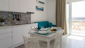 Una cocina moderna con armarios blancos, un salpicadero de azulejos y un comedor con una mesa dispuesta para dos personas.