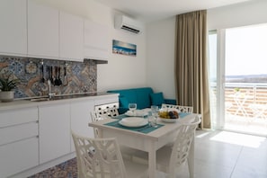 Een moderne keuken met witte kasten, een betegelde achterwand en een eethoek met een tafel gedekt voor twee personen.