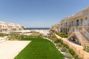 Un hotel con varios balcones, piscina y jardín bien cuidado.