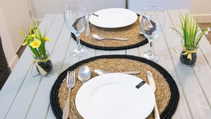 A table set with white plates, silverware, and glassware on a white wooden table with woven placemats. - Le Pied-à-Terre - Wifi - Centre-ville (Laval)