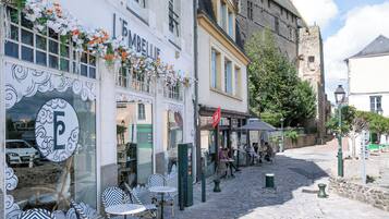 Une rue pavée avec des tables et des chaises installées à l’extérieur, devant un café appelé « L’EMBELLIE ».