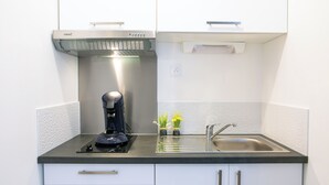 A compact kitchen with a coffee maker, a sink, and two small flower pots on the counter. - Le Pied-à-Terre - Wifi - Centre-ville (Laval)