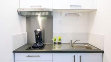 Une petite cuisine équipée comprenant une machine à café, un évier et un petit plan de travail.