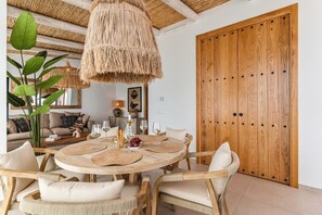 Un coin repas comprenant une table ronde, des chaises, un luminaire suspendu et une porte en bois.