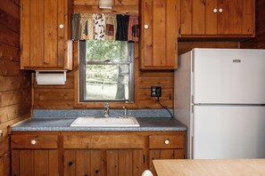 Una cocina con armarios de madera, un lavamanos doble y un refrigerador blanco.