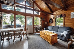 Un interior acogedor de cabaña con comedor, sofá y un cofre de madera.