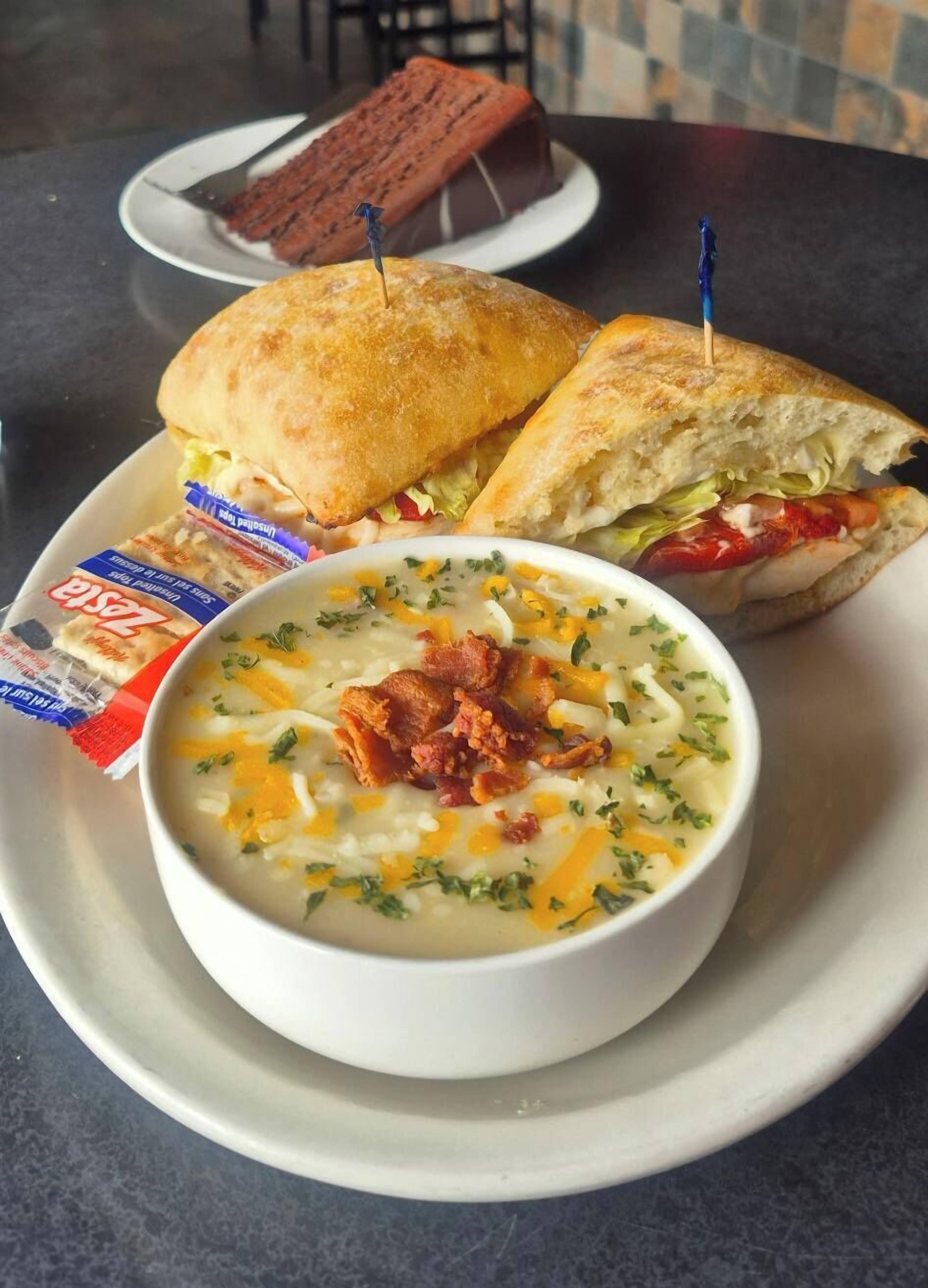 A meal consisting of a sandwich, a bowl of soup, and a brownie on a plate.