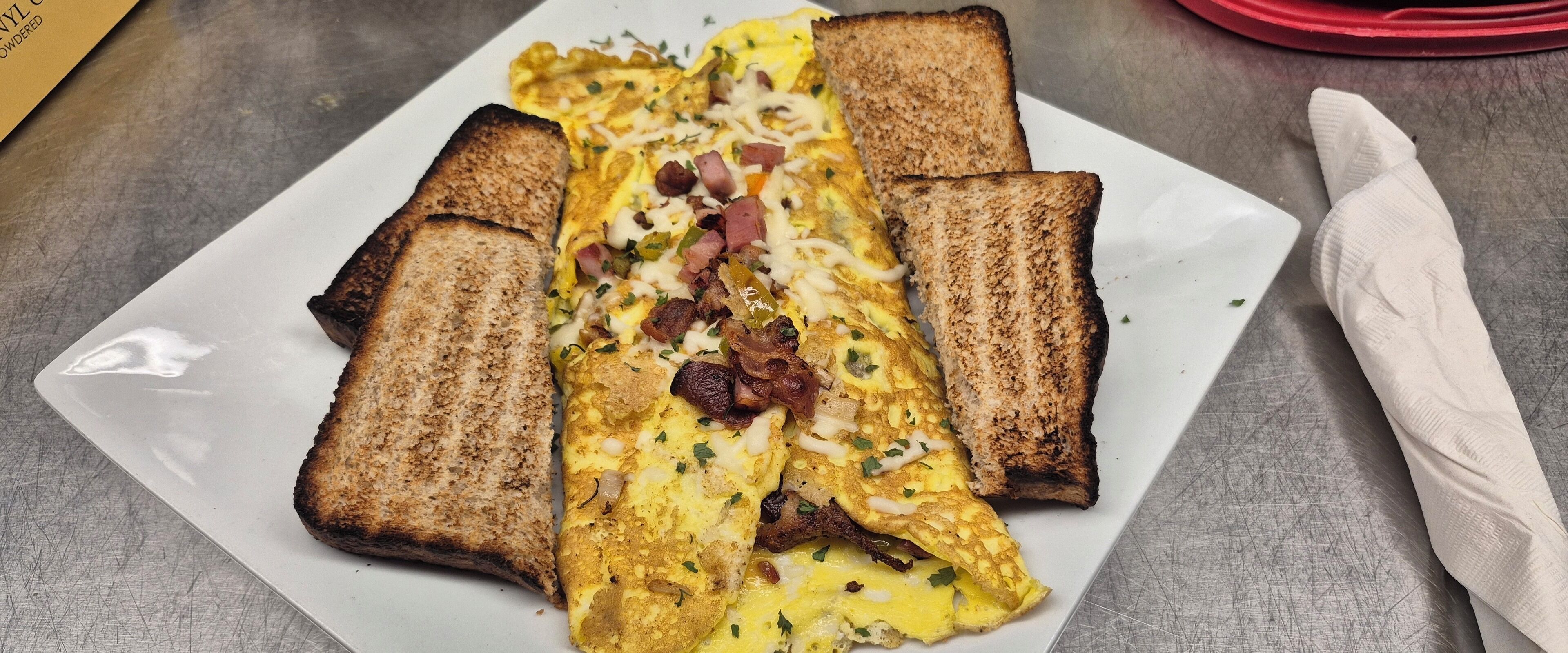 Un plato con tortilla, tocino y pan tostado.