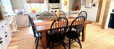 A dining area with a wooden table and chairs, a ceiling fan, and a television on the wall.