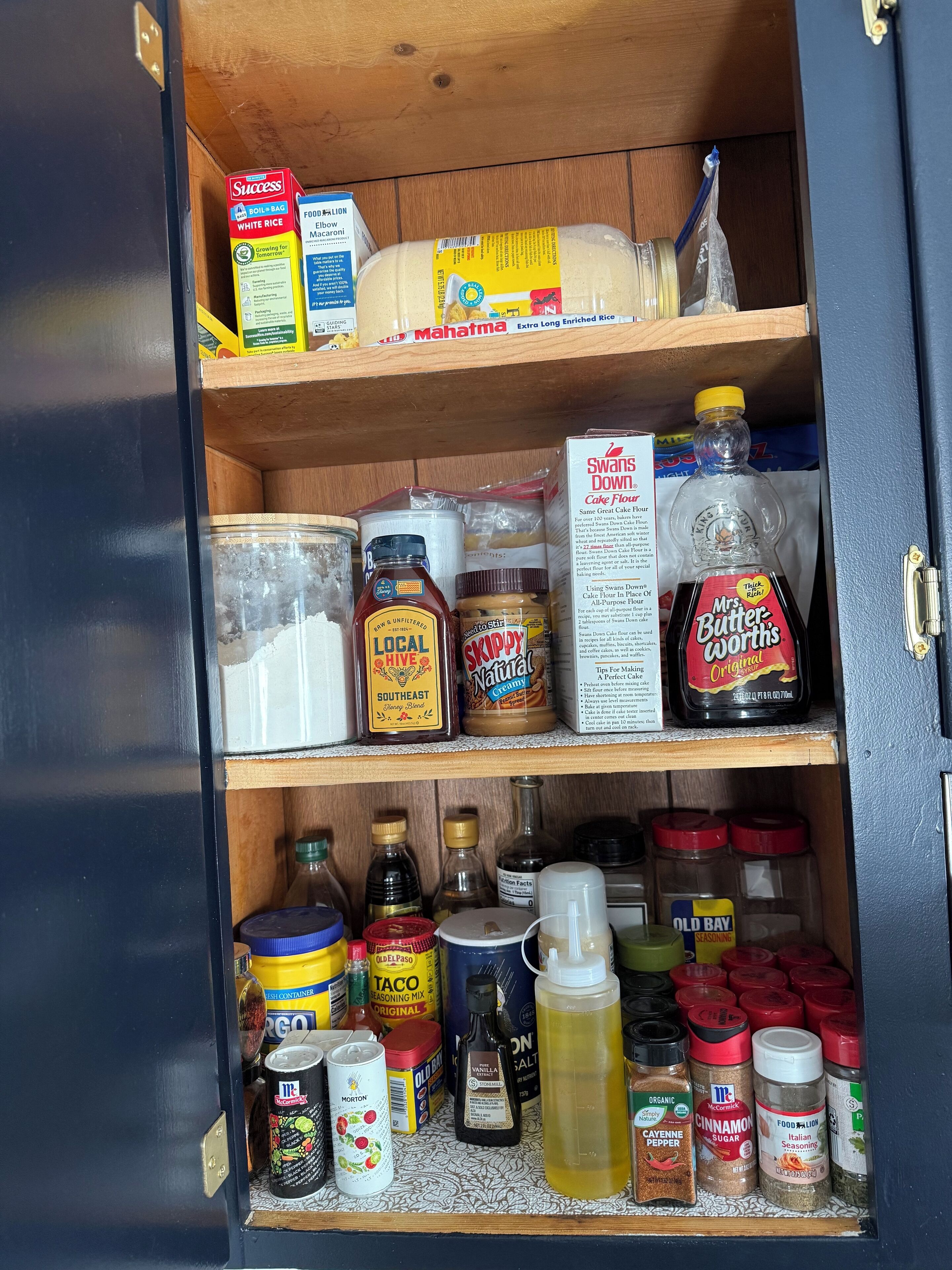 Eine Speisekammer mit verschiedenen Lebensmitteln, darunter Reis, Nudeln, Gewürzen und Backzutaten.