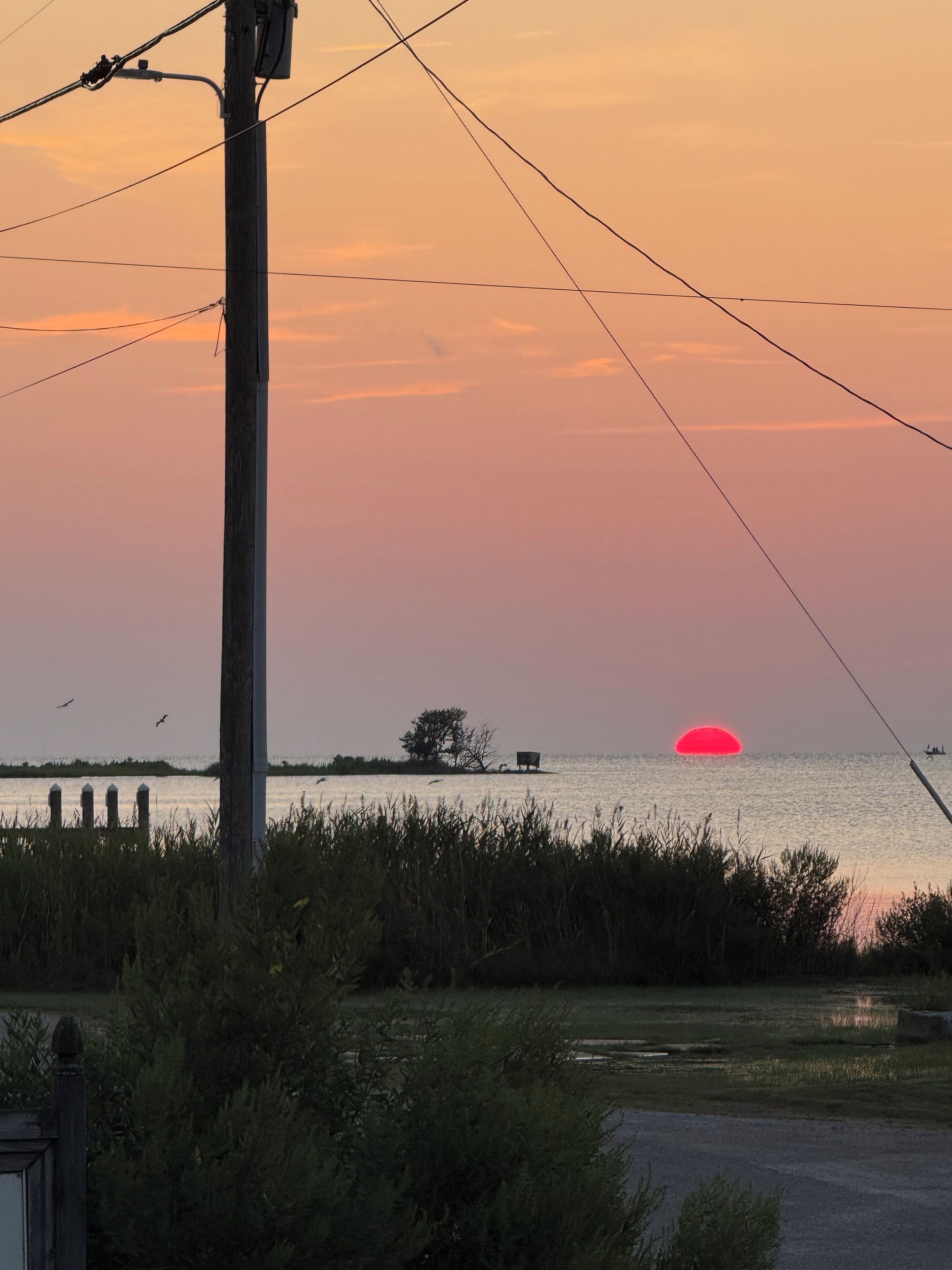 Ein Sonnenuntergang über einem Gewässer mit einer Anlegestelle und einem Boot.