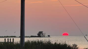 Ein Sonnenuntergang über einem Gewässer mit einer Anlegestelle und einem Boot.