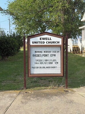 Ein Kirchschild mit dem Namen 'EWELL UNITED CHURCH' sowie Angaben zu Gottesdiensten und Kontaktinformationen.
