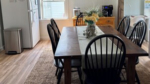 A dining area with a wooden table and chairs, a coffee machine, and a trash bin.