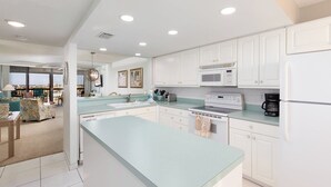 Una cocina moderna con armarios blancos, una isla grande y vistas a un balcón.
