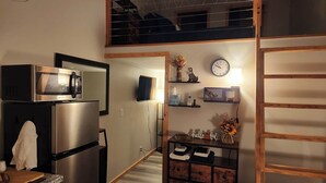 A compact kitchen with a microwave, refrigerator, and a small wooden cabinet.