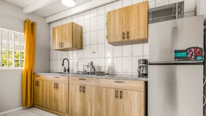 Moderni keittiö, jossa on puiset kaapit, ruostumattomasta teräksestä valmistettu jääkaappi ja kahvinkeitin.