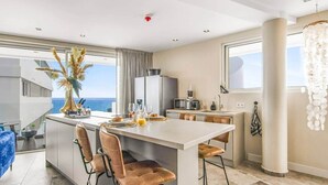 A modern kitchen with a central island, bar stools, a dining table, and a view of the sea. - LUX 3 BR Sub Penthouse One Mambo Beach (Willemstad)