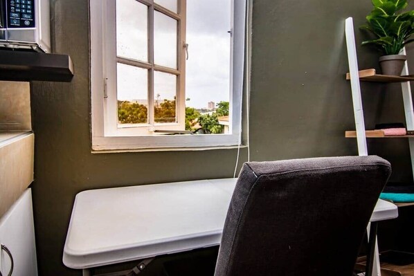 A room with a window, a white desk, and a chair.