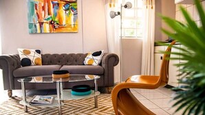 Ein Wohnzimmer mit einer Couch, einem Couchtisch und einem auffälligen orangefarbenen Sessel.