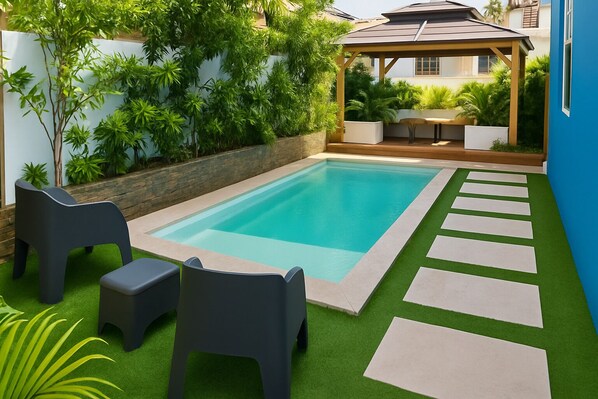Una piscina rectangular con una terraza de madera y una pérgola.