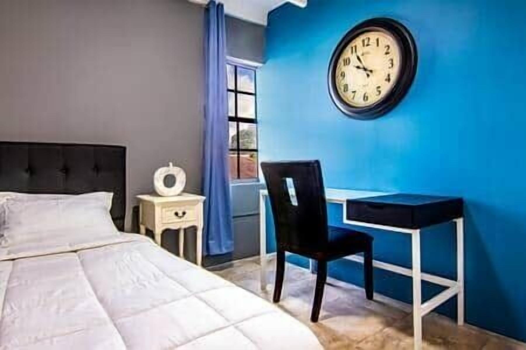 Un dormitorio con cama, escritorio y silla.