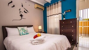 Un letto rifatto con lenzuola bianche, un cuscino decorativo e un asciugamano con fiori.
