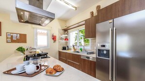 A modern kitchen with stainless steel appliances, a large island with breakfast items, and a view of the outdoors. - Villa Alexander - Three Bedroom Villa, Sleeps 6 (Paralimni)