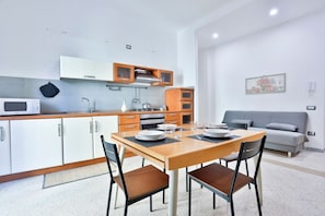 Eine moderne Küche mit weißen Schränken, einer Holz Arbeitsplatte und einem Essbereich mit Tisch und Stühlen.