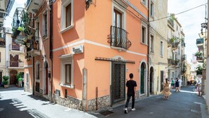 Une rue bordée d’immeubles, un homme qui marche et une femme en robe.