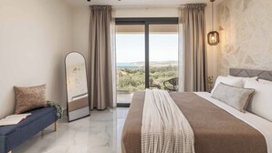 Une chambre avec un grand lit, un canapé, un miroir et une vue sur l’extérieur.