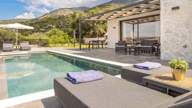 Un espace piscine doté de chaises longues, d’une pergola et offrant une vue sur les montagnes.