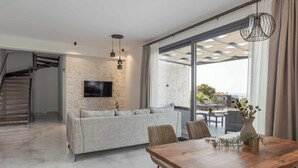 Un salon moderne avec un canapé, une table à manger et un téléviseur fixé à un mur à texture.