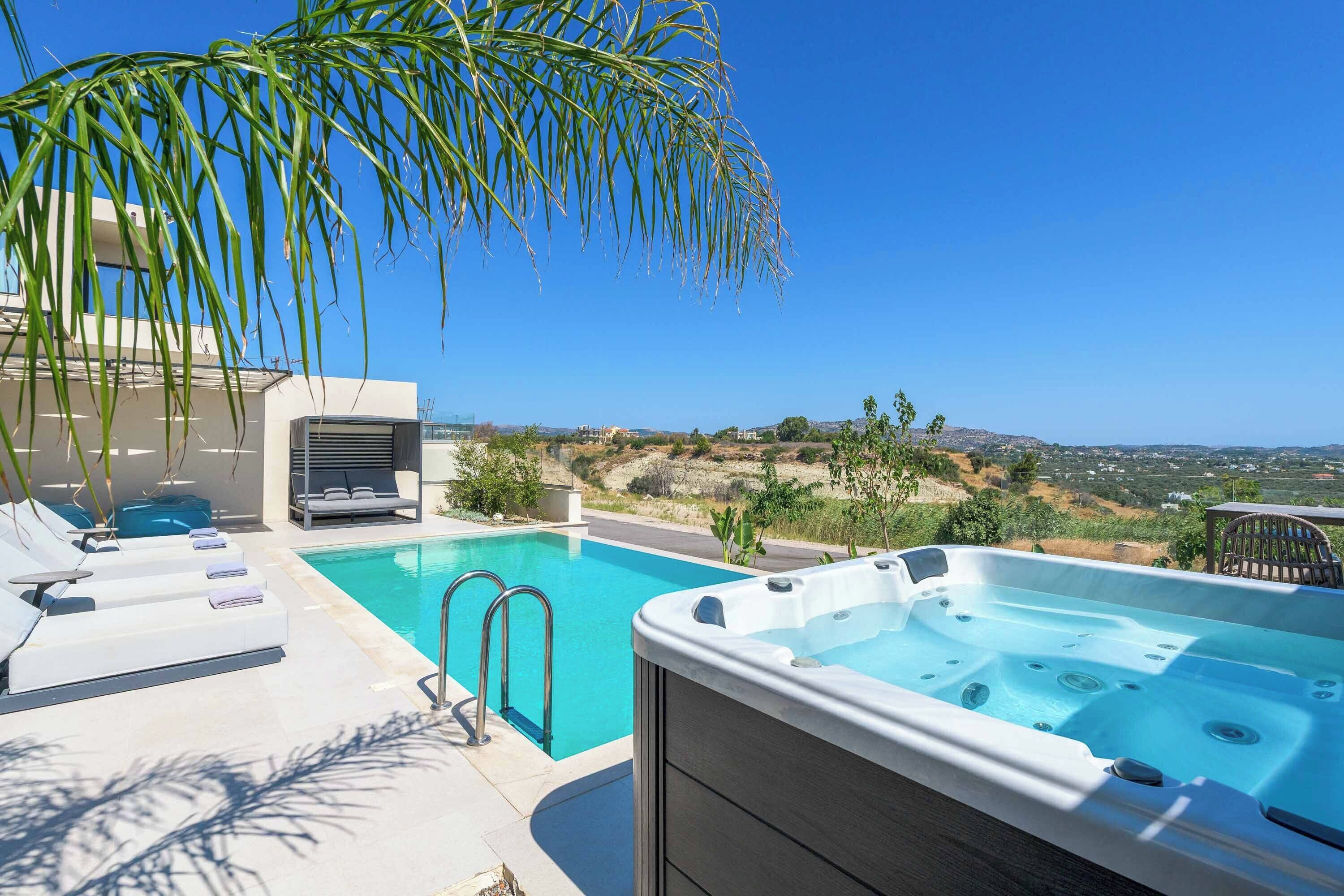 Uma área de piscina no terraço com espreguiçadeiras, uma banheira de hidromassagem e vista para a paisagem ao redor.